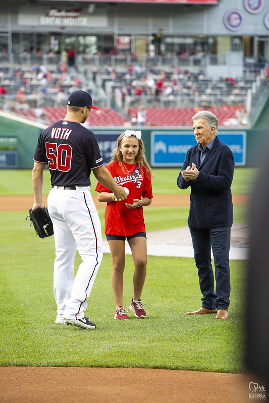Courage Award Honoree Maddison Raines throws the first pitch at a Washington Nationals game against the Phillies, alongside John Walsh and Nationals pitcher Austin Voth.