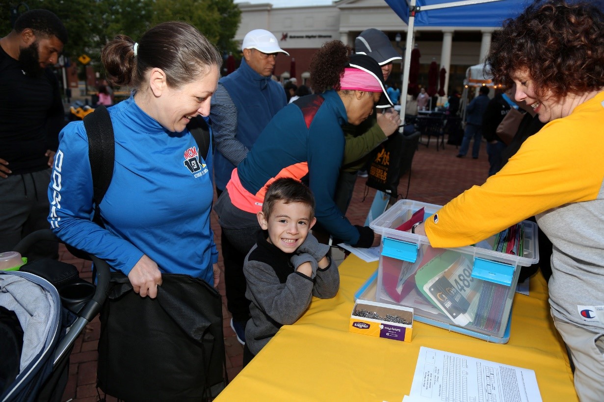 runners picking up race packets before 5k