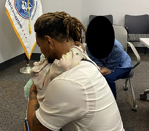 Majesty found safe Image of Majesty and her father hugging, you mostly see him- a black man with brown and blonde dreads tied back hugs his daughter so you can just see her arms around his neck and they sit in a Federal office with a field opperations flag of white and blue in the background.