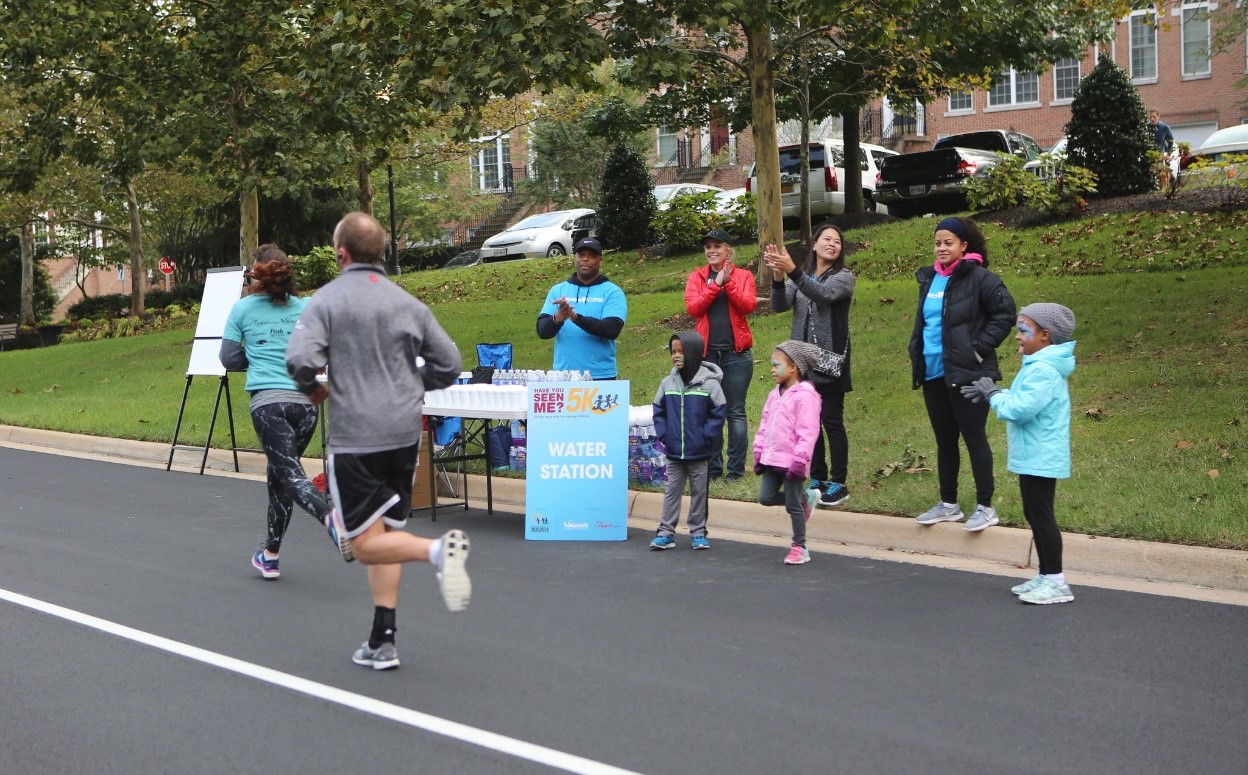 Volunteers cheering on runners and handing out water along route.