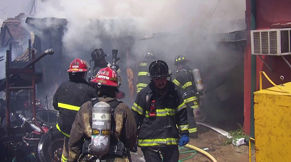 firefighters walking around ashes of burned house