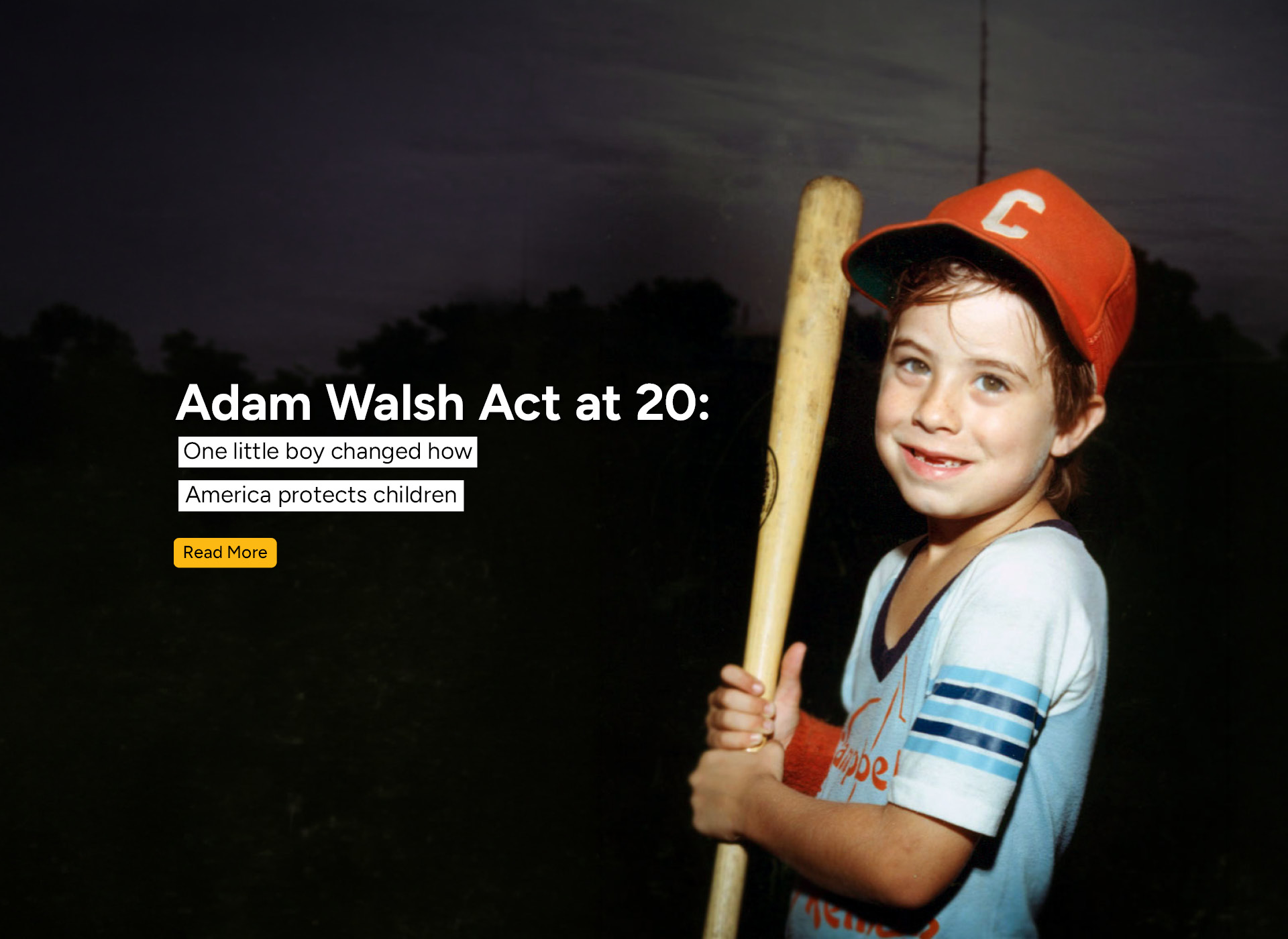 adam smiling, holding baseball bat and wearing red hat
