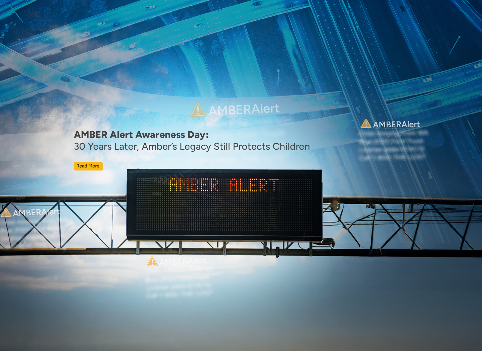 highway sign with amber alert in foreground; blue toned background of overhead shot of highway bypasses