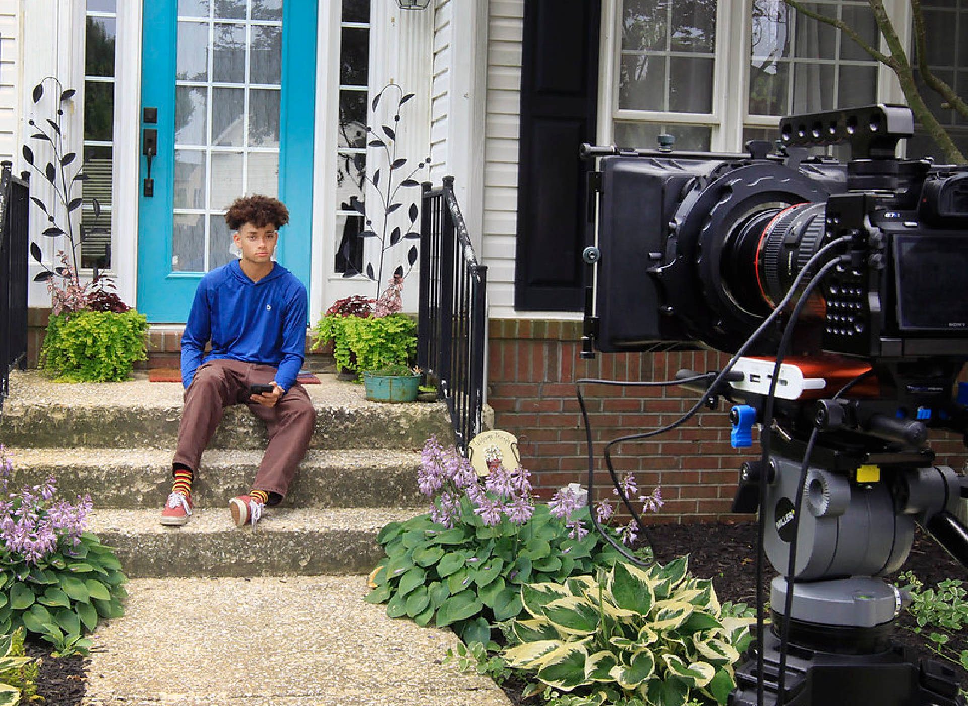 Teen actor sitting on stairs in front a video camera