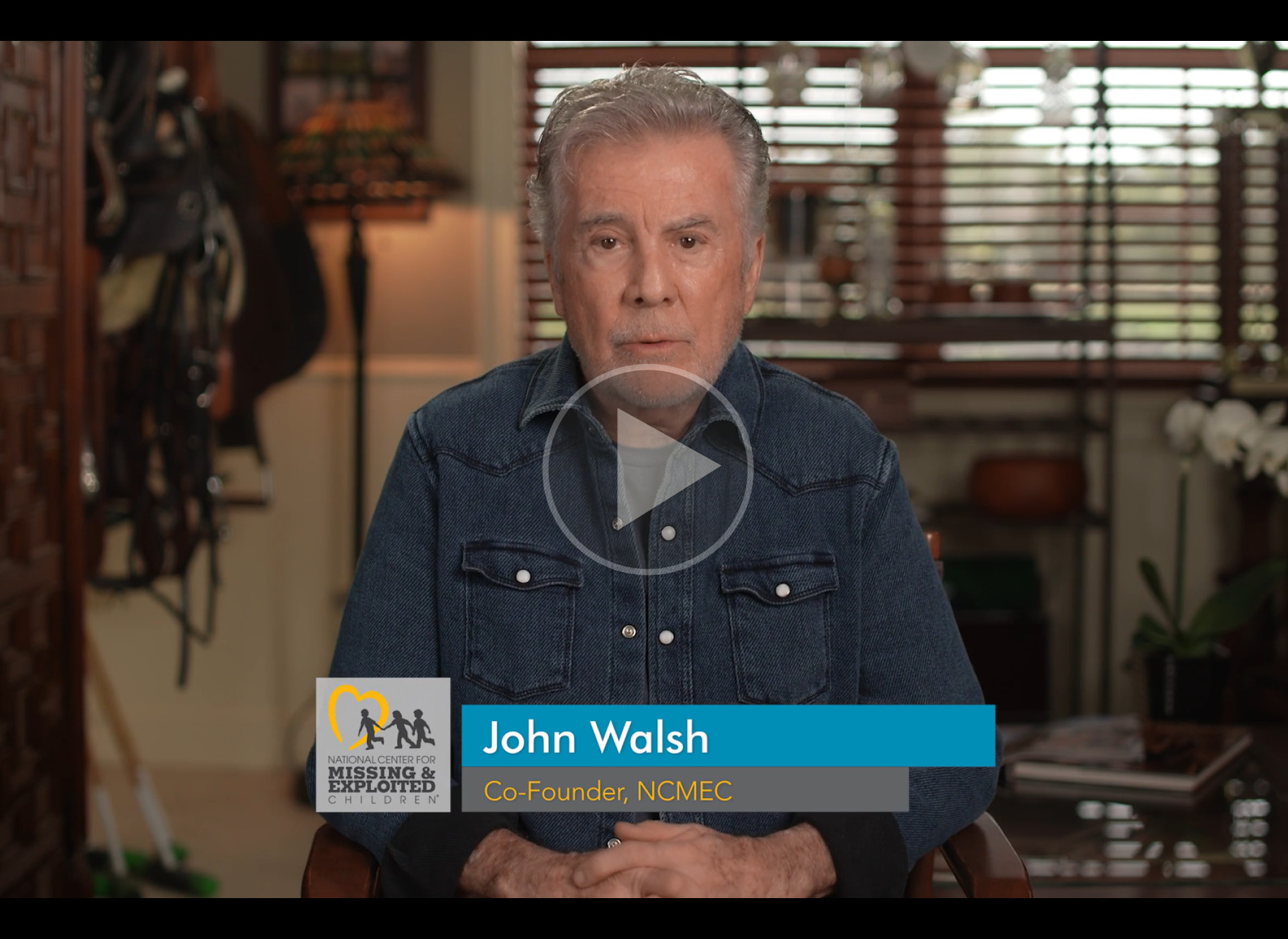 john walsh wears denim shirt and sits at desk