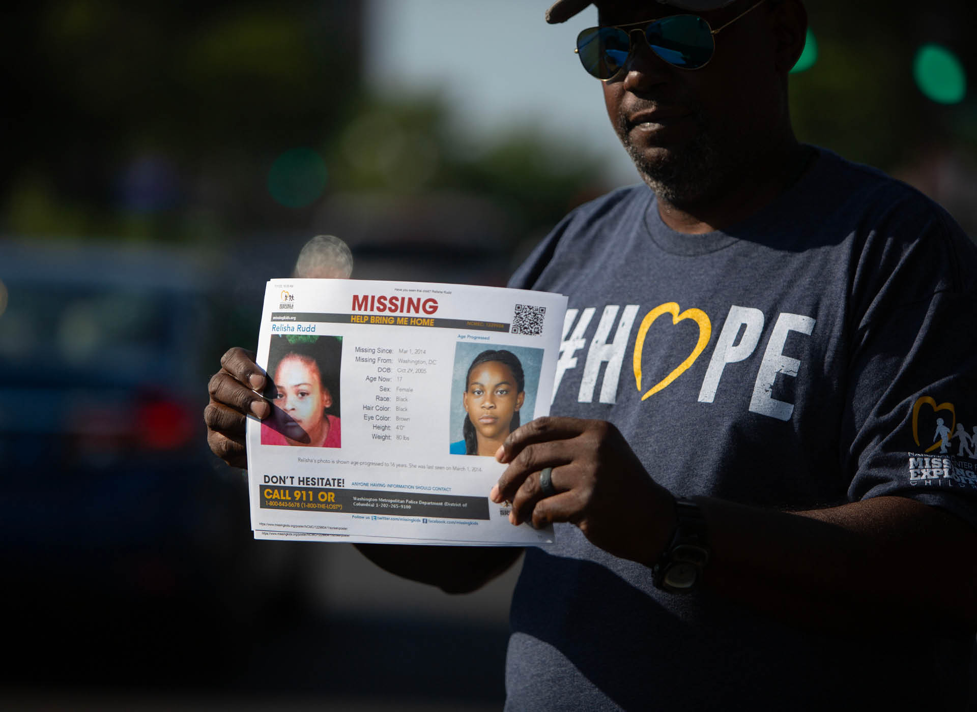 man in gray NCMEC Hope shirt holds relisha's missing poster
