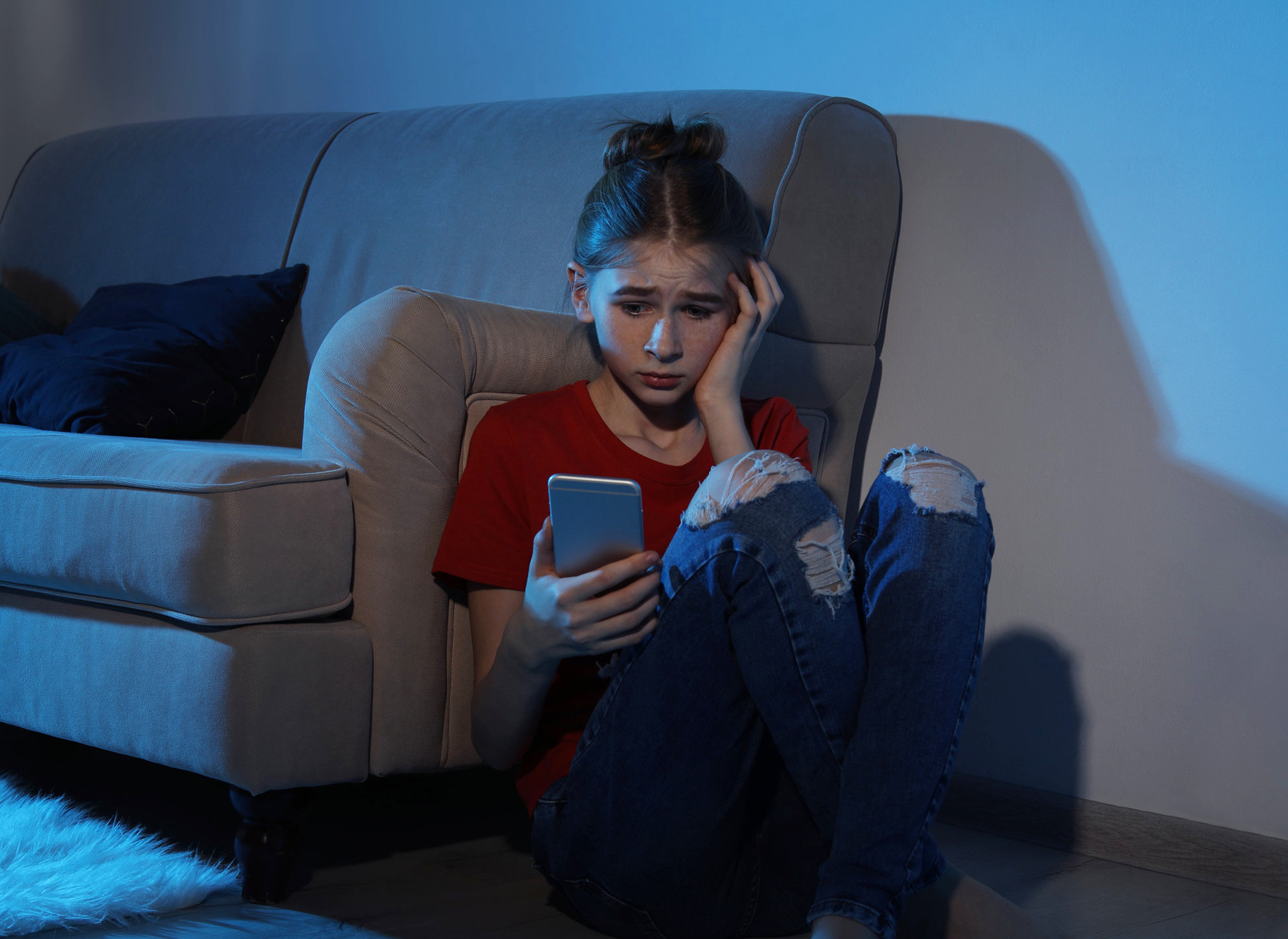 Teen girl sitting on the floor watching a cell phone