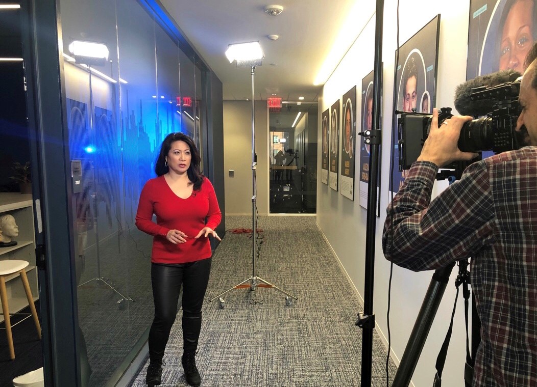 Asian american woman in red top and black pants being filmed for TV