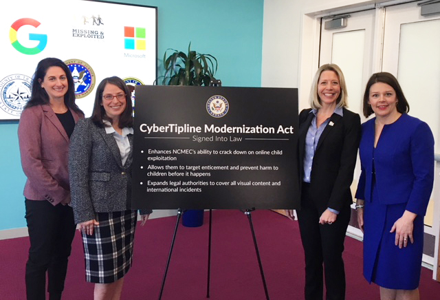 Four caucasian women standing by a black poster with white text