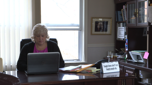 Blonde woman sits at desk with computer in office